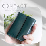 片手に収まるコンパクトなピンクの牛革財布を手で持つ