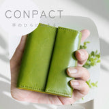 コンパクトな緑の牛革財布が手の平に収まっている