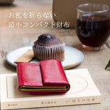 赤いバイカラーのコンパクト財布がカフェにある様子