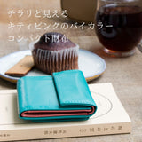 青いコンパクト財布がカフェに置かれていて、バイカラーのピンクがちらりと見える様子
