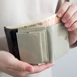 グレーのパイソン蛇革財布を手に持ちお札を取り出す様子|コンパクトで手のひらサイズ