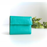 片手に収まるコンパクトな青(ターコイズブルー)の牛革財布の正面写真