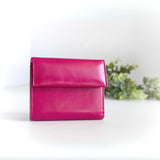 片手に収まるコンパクトなピンクの牛革財布の正面