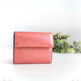 片手に収まるコンパクトなピンクの牛革財布の正面