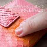 ピンクのパイソン蛇革財布を指でなぞっているところ