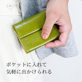 手のひらサイズお緑のコンパクト財布をポケットに入れようとしている様子