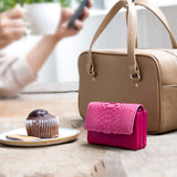 大人ピンクの、小さなカードサイズのコンパクト財布がカフェにある様子