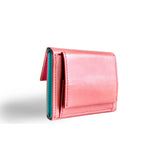 片手に収まるコンパクトなピンクの牛革財布の小銭入れ部分