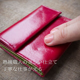 赤い、小さいお財布を指で押さえて柔らか輪を高めている