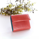 片手に収まるコンパクトなピンクの牛革財布のバイカラーが見える