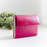 片手に収まるコンパクトなピンクの牛革財布の斜めから見たところ