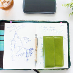 緑の牛革財布がノートの上に添えられている様子|超軽量で大容量な二つ折り財布