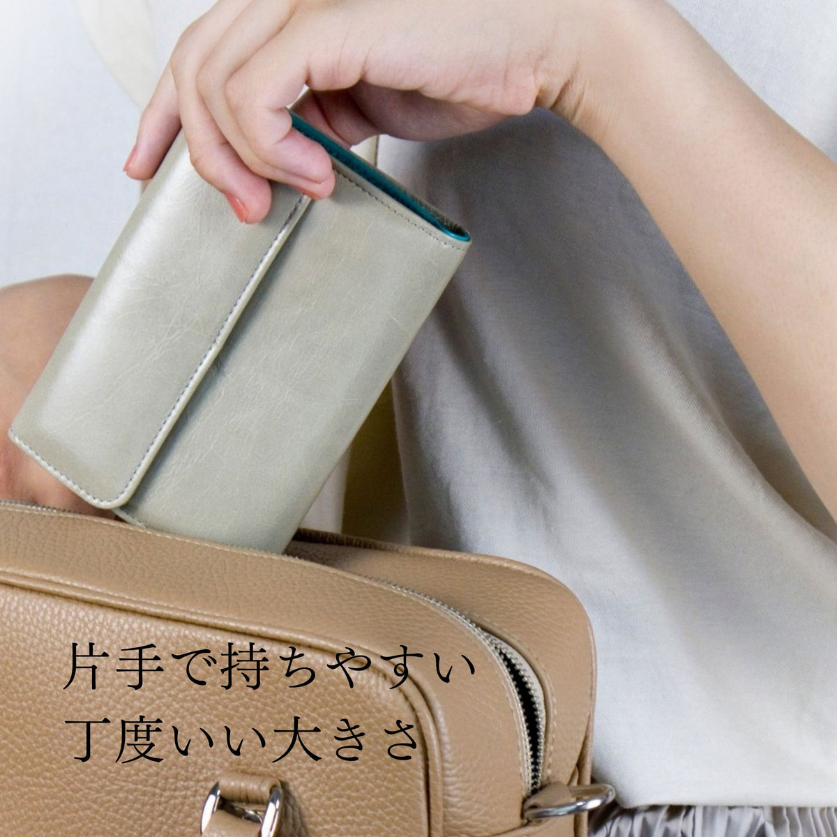 ライトグレーとターコイズブルーのバイカラーの二つ折り財布をバッグに入れている様子。サイズが伝わる。