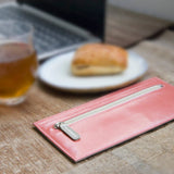 ピンクとグレーのバイカラーの厚さわずか2mmの長財布がカフェにある様子