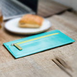 青と緑のバイカラーの厚さわずか2mmの長財布がカフェにある様子