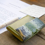 緑のコンパクト財布、蛇革パイソン。カフェの上に素敵に置かれているメインビジュアル