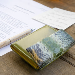 緑のコンパクト財布、蛇革パイソン。カフェの上に素敵に置かれているメインビジュアル