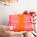 ピンクのパイソン蛇革財布を手に持った様子|超軽量で大容量な二つ折り財布
