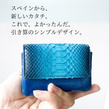 美しいブルーのグラデーションが特徴の蛇革の小さなカードサイズのコンパクト財布を手のひらに置き、大きさが分かりやすくなっている様子