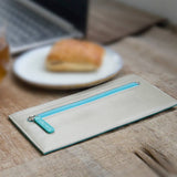 グレーと青のバイカラーの厚さわずか2mmの長財布がカフェにある様子