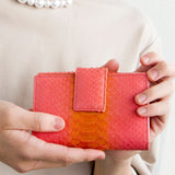 ピンクのパイソン蛇革財布を手に持った様子|超軽量で大容量な二つ折り財布