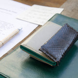 グレーのパイソン蛇革財布を机の上に|コンパクトで手のひらサイズ