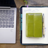 黄緑の二つ折り財布が仕事場のテーブルに置かれている様子