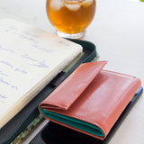 片手に収まるコンパクトなピンクの牛革財布の代表写真