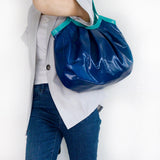 ネイビーの本革、レザーのトートバッグを肩にかける女性