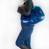 ネイビーの本革、レザーのトートバッグを持つ女性のよこむきの様子