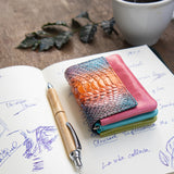 蛇革のミニ財布をカフェで使っている様子 4色染めのパイソンが美しい。