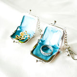 パイソン蛇革のがま口に指輪とイヤリングを入れている様子