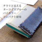 グレーとターコイズブルーのバイカラーの極小二つ折り財布がカフェにある様子