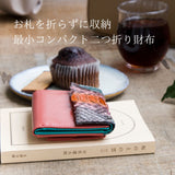 パイソン蛇革、4色手染めの唯一無二のコンパクト財布がカフェにおしゃれに置いてある様子