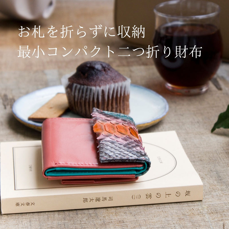 パイソン蛇革、4色手染めの唯一無二のコンパクト財布がカフェにおしゃれに置いてある様子