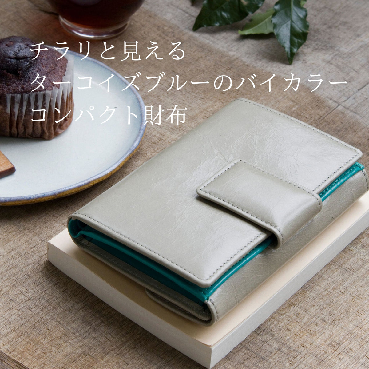ライトグレーとターコイズブルーのバイカラーの二つ折り財布がカフェにある様子