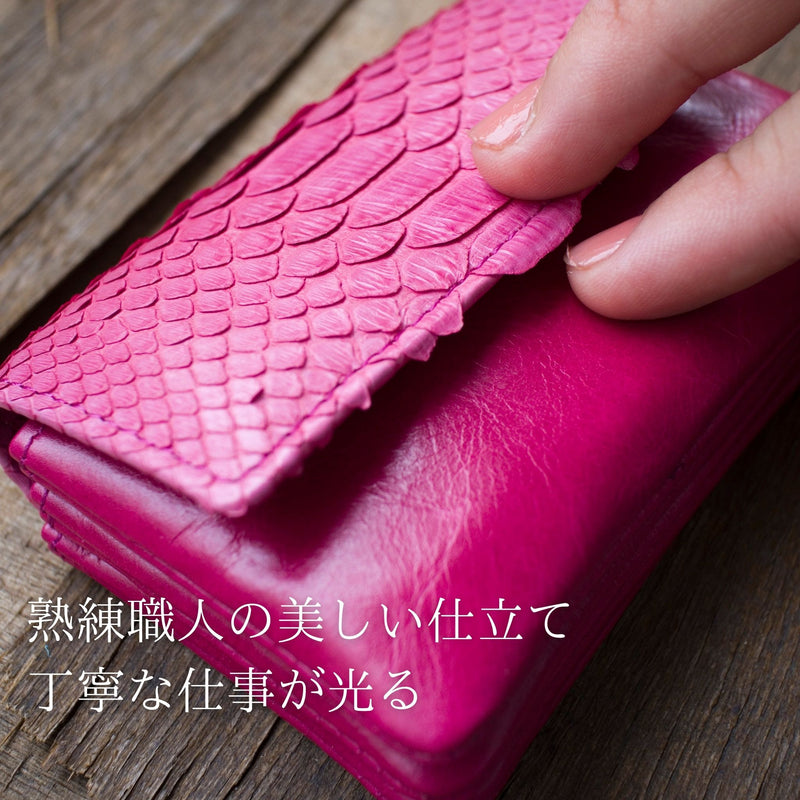大人ピンクの、小さなカードサイズのコンパクト財布をそっと指で押して、柔らかい革が分かる様子