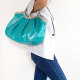 青い総革の軽量トートバッグを持つ女性を横からみた図