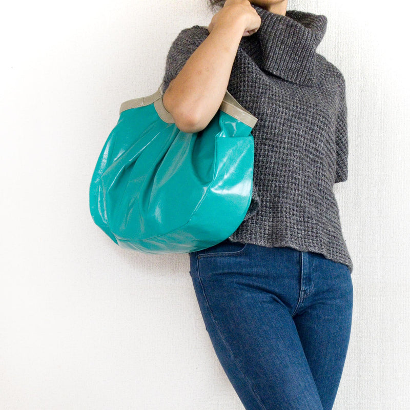 青い総革の軽量トートバッグを持つ女性