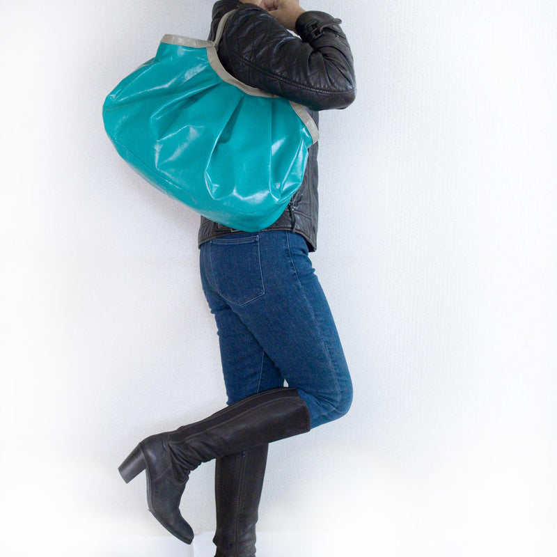 青い総革の軽量トートバッグを持つ女性