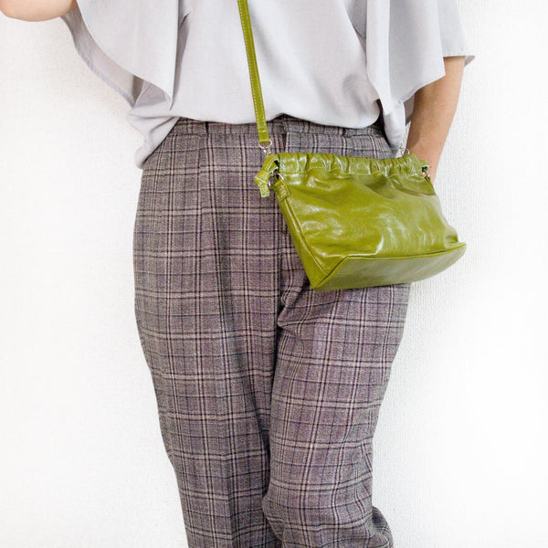 グリーンのミニバッグを肩から下げている様子